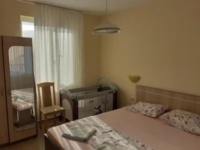 a bedroom with a bed and a chair and a window at Apartments Sea Sounds in Pomorie