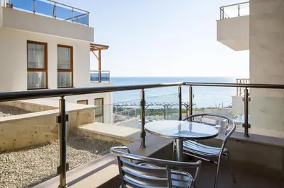 a balcony with a table and chairs and the ocean at White Cliffs, Byala in Byala