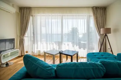 a living room with a blue couch and a large window at White Cliffs, Byala in Byala