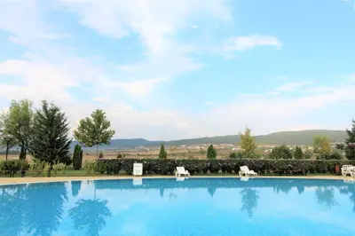 a large blue swimming pool with chairs and trees at Holiday-Orchid Menada Apartments in Sunny Beach