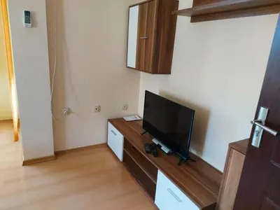 a living room with a flat screen tv on a dresser at Уютно и просторно студио in Ravda