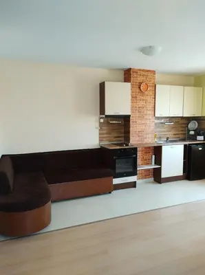 a living room with a couch and a kitchen at Уютно и просторно студио in Ravda