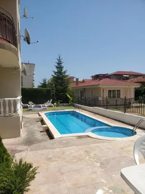 a swimming pool in a yard next to a house at Уютно и просторно студио in Ravda