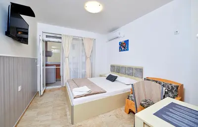 a small bedroom with a bed and a tv at Студио Патрисия in Pomorie