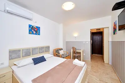 a bedroom with a large bed and a table at Студио Патрисия in Pomorie