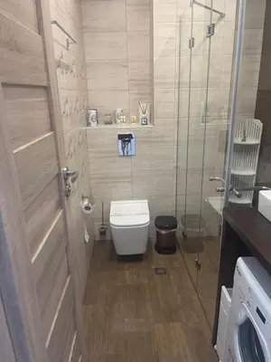 a bathroom with a toilet and a glass shower at Къмпинг градина луксозен апартамент in Chernomorets