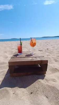 a wooden table on the beach with two cocktails at Къмпинг градина луксозен апартамент in Chernomorets
