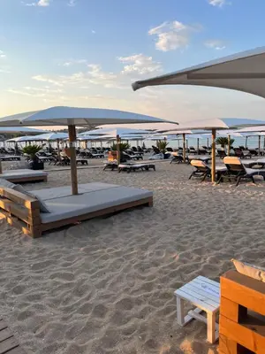a beach with tables and umbrellas on the sand at Къмпинг градина луксозен апартамент in Chernomorets