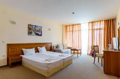 a hotel room with a large bed and a chair at Tiva del Mar Beach Hotel in Sveti Vlas