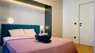 a bedroom with a bed with a blue head board at Апартамент Жасмин с частен гараж - Jasmin Apartment with private garage in Varna City