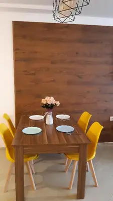 a wooden table with yellow chairs around it at Апартамент Адикт in Sozopol