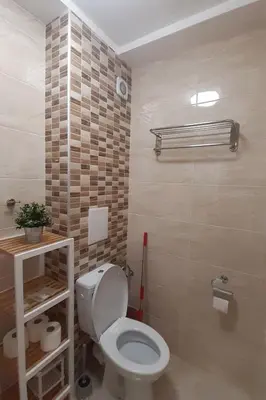 a bathroom with a toilet and a tiled wall at Апартамент Адикт in Sozopol