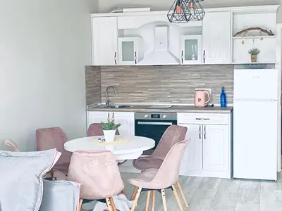 a kitchen with a table and pink chairs in a room at Apartments in complex PANORAMA in Chernomorets