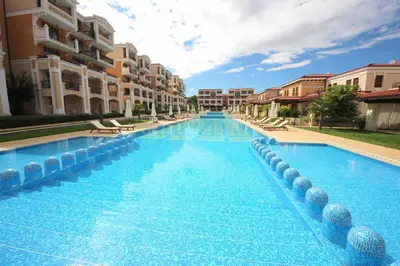 a large swimming pool with chairs and buildings at Green Life Beach Resort Apartment in Sozopol