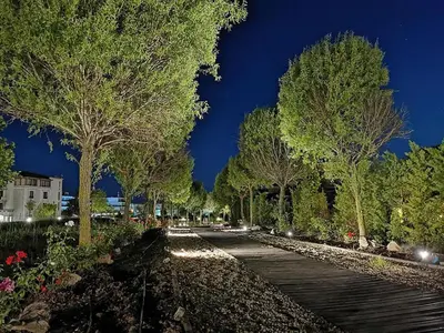 a walkway in a park at night with trees at Green Life Beach Resort Apartment in Sozopol