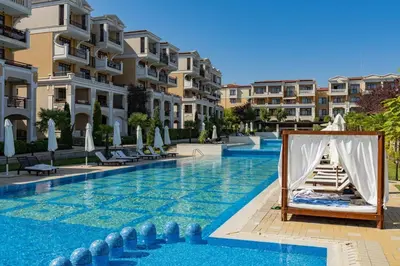a hotel swimming pool with a bed and some buildings at Green Life Beach Resort Apartment in Sozopol