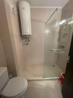 a bathroom with a shower with a toilet and a glass door at private apartments in Apolon in Ravda