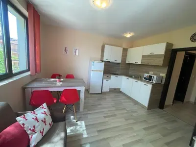 a kitchen with a table and red chairs in a room at private apartments in Apolon in Ravda