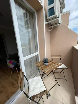 a balcony with a table and chairs and a window at Marea Garden apartments in Ravda