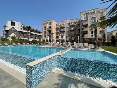 a swimming pool with chairs and buildings in the background at Marea Garden apartments in Ravda