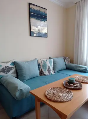 a living room with a blue couch and a table at Lilia Sun Apartment in Sozopol