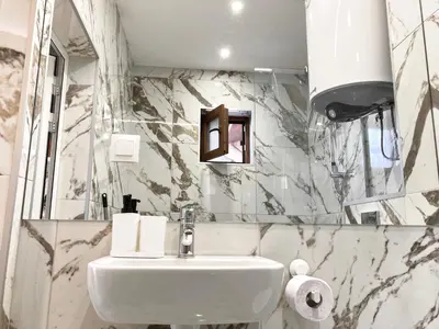 a white sink in a bathroom with marble walls at Dune Apartment Nessebar in Nesebar