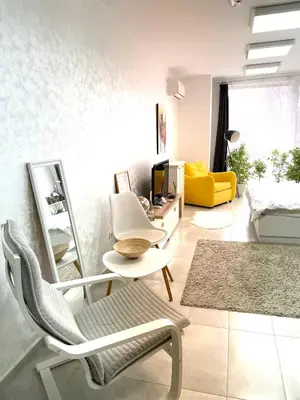 a living room with a chair and a yellow couch at Felicity Super Central Apartment in Burgas City