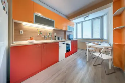 a kitchen with orange cabinets and a white table at Daisy - 3 Room and kitchen apartment in Lazur in Burgas City