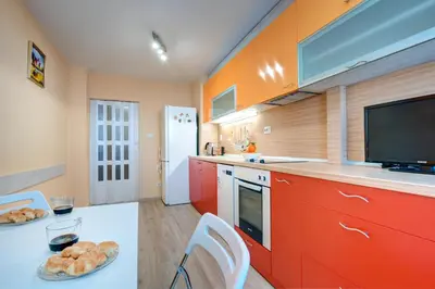 a kitchen with red cabinets and a flat screen tv at Daisy - 3 Room and kitchen apartment in Lazur in Burgas City