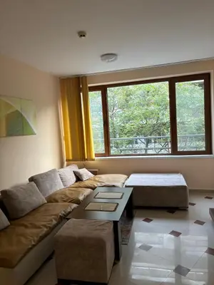 a living room with a couch and a large window at Студио Бургас 2 in Burgas City