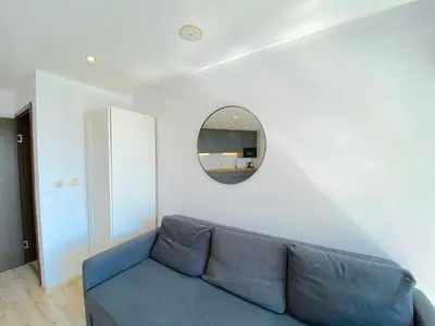 a living room with a blue couch and a mirror at Paradiso Aparthotel - Private apartment -BSR-2 in Nesebar
