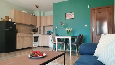 a living room with a table and a kitchen with blue walls at Soulful Apartments - AlmaLetta in Varna City