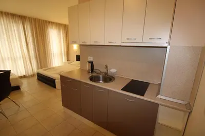 a kitchen with a sink and a room with a bed at Menada Casa del Sol Apartments in Sunny Beach