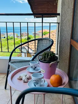 a table with two cups and oranges on a balcony at Sunrise place Eva in Sozopol