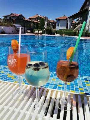 three wine glasses sitting on a table next to a swimming pool at Sunrise place Eva in Sozopol