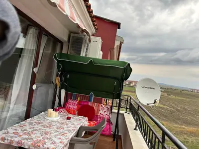 a table and chairs on a balcony with a view of a field at Art studio Marina Cape-private host in Ravda