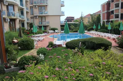 a courtyard with a pool and chairs and umbrellas at Apart complex Starfish със собствено паркомясто in Sveti Vlas