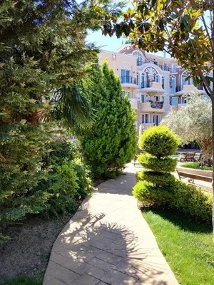 a walkway in front of a large building with trees at Marina Studio in Ravda