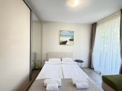 a bedroom with a large white bed and a mirror at Marina Studio in Ravda
