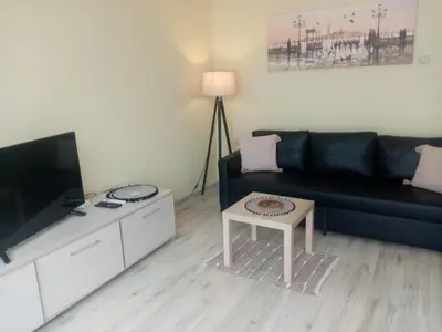 a living room with a black couch and a table at Spacious apartment 