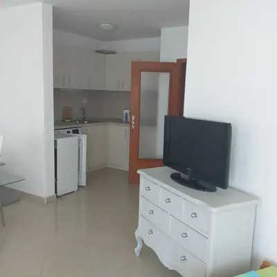 a living room with a television on a dresser with a kitchen at Z&Z Apartment in Sozopol