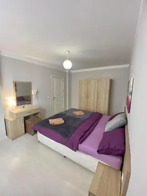 a bedroom with a purple bed and a television at Apartman Kuba in Primorsko