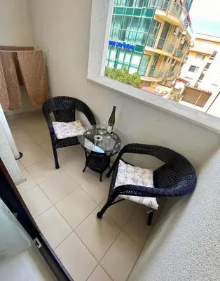 a balcony with a glass table and chairs and a window at Apartman Kuba in Primorsko