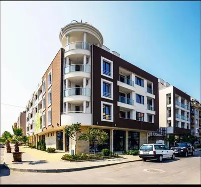 a large building with a car parked in front of it at Apartman Kuba in Primorsko