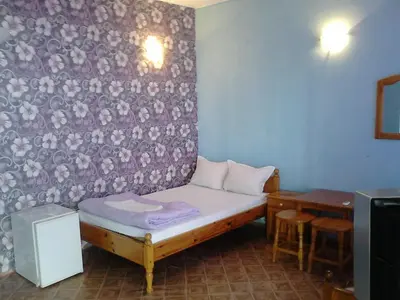 a small room with a bed and a table at Вила Синя Иглика in Kosharitsa