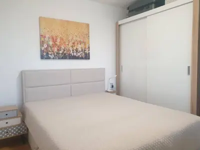 a bedroom with a white bed and a painting on the wall at Seaside 1-BR Apartment with Pool Access in Byala