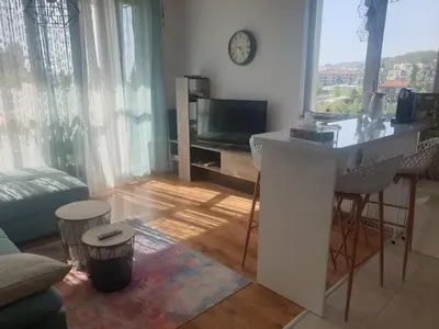 a living room with a table and a tv in it at Seaside 1-BR Apartment with Pool Access in Byala