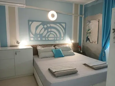 a bedroom with a large bed with blue walls at Апартамент BLUE SUMMER - уют, близо до морето in Burgas City