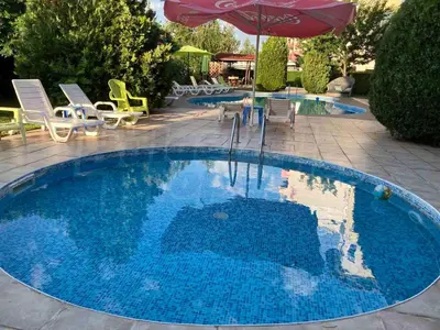 a large blue pool with chairs and an umbrella at Sunny Gardens in Sunny Beach