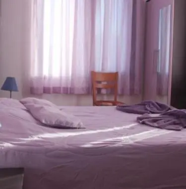 a bedroom with a bed and a chair and a window at Къща за гости АЛЛА in Byala